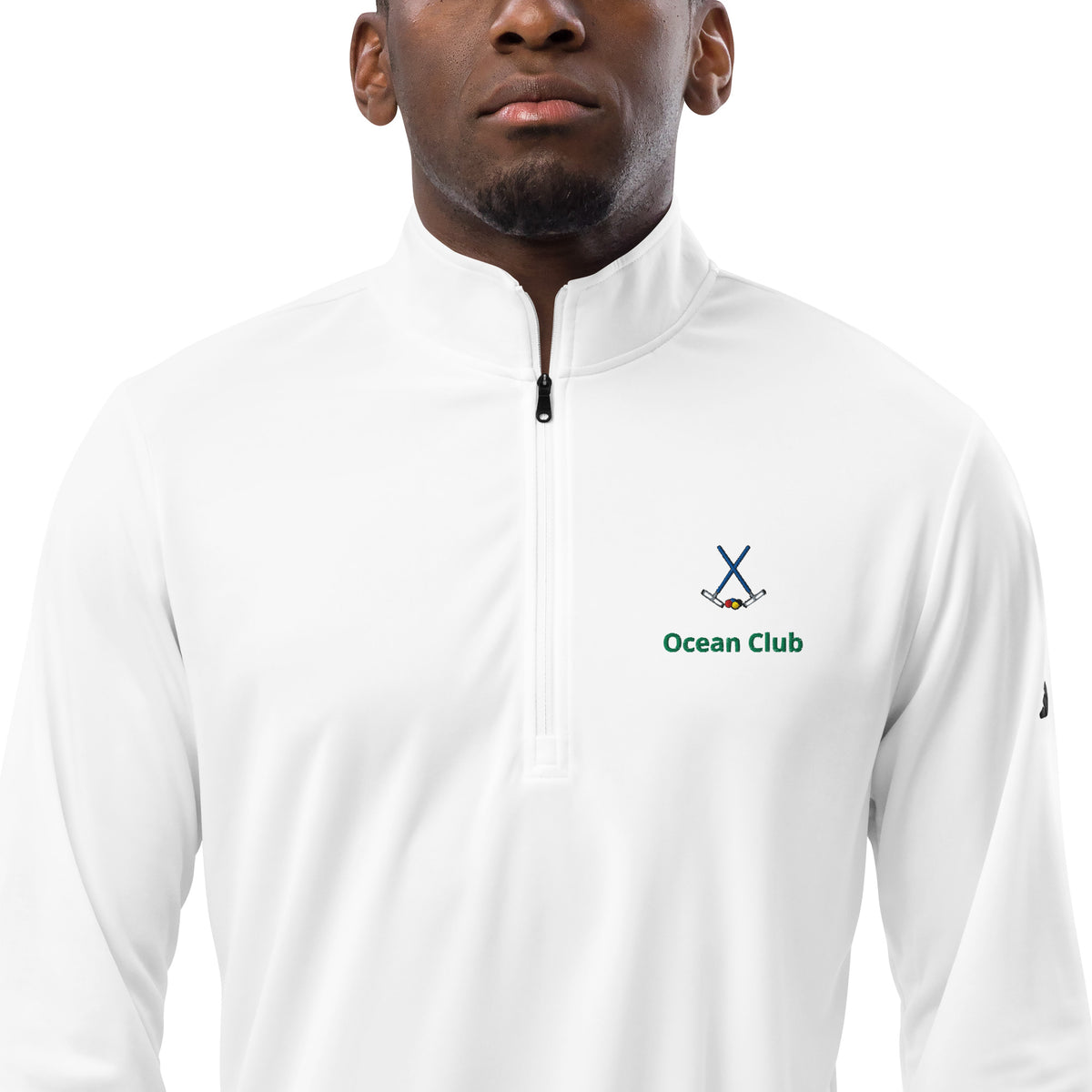 A man wearing a white long-sleeve Adidas quarter-zip white pullover with a cross croquet mallets logo on the left chest.