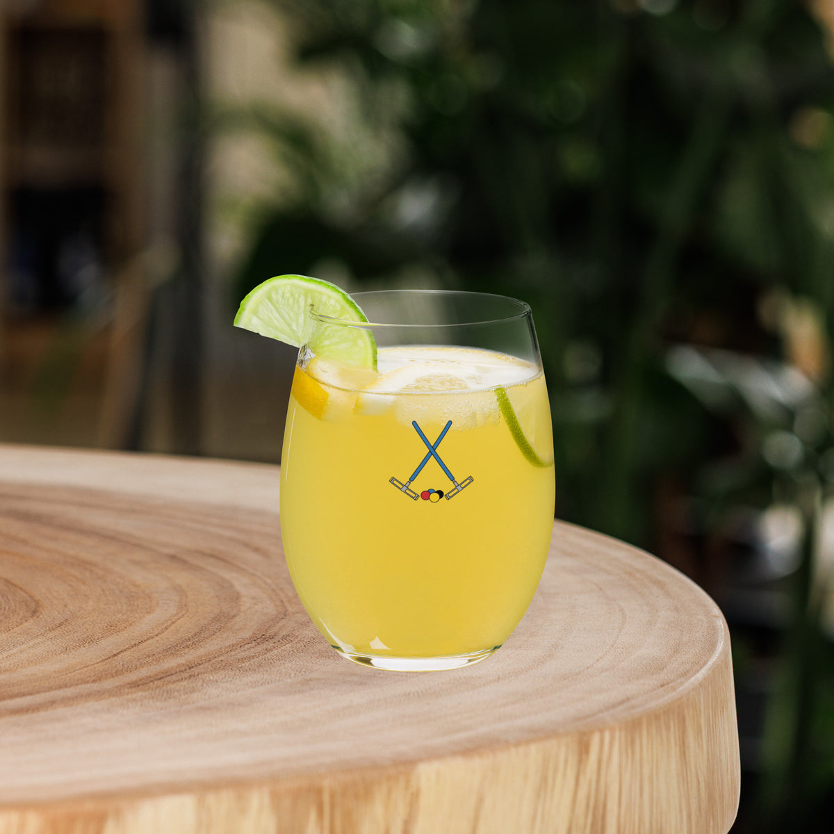 a stemless wine glass with a croquet themed logo of crossed mallets